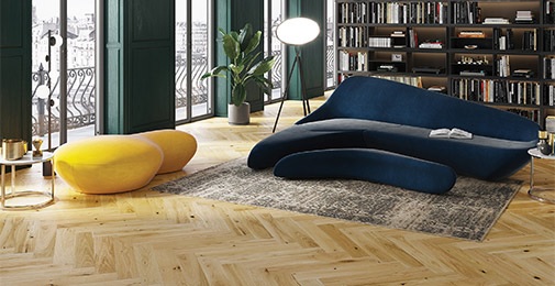 Fiskebeinsgulv i stue med blå sofa