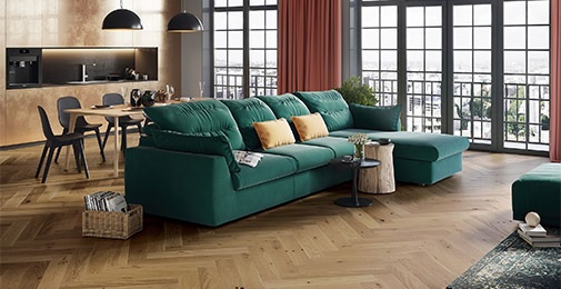 Fiskebeinsgulv i stue med grønn sofa